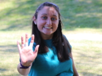 MaryClaire Attisano holds up a "high five," which is the symbol of Peer Mentors